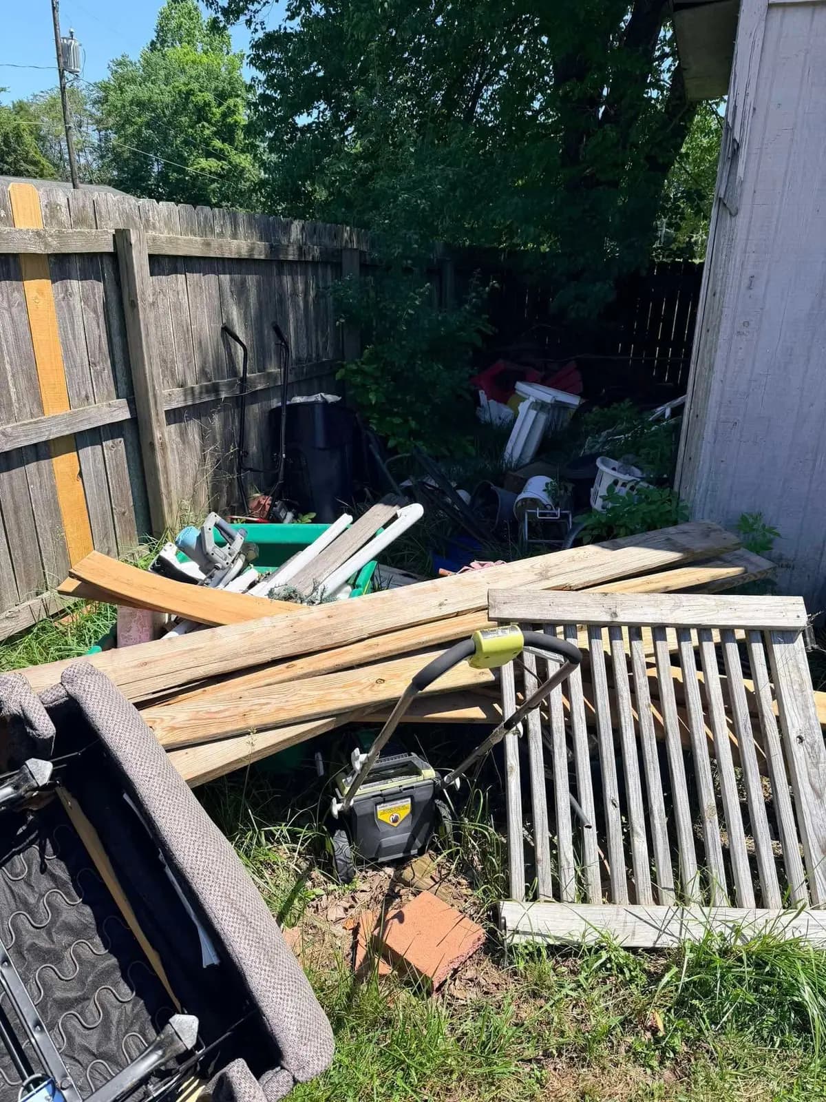 Backyard full of yard debris, old lumber, and clutter before cleanout